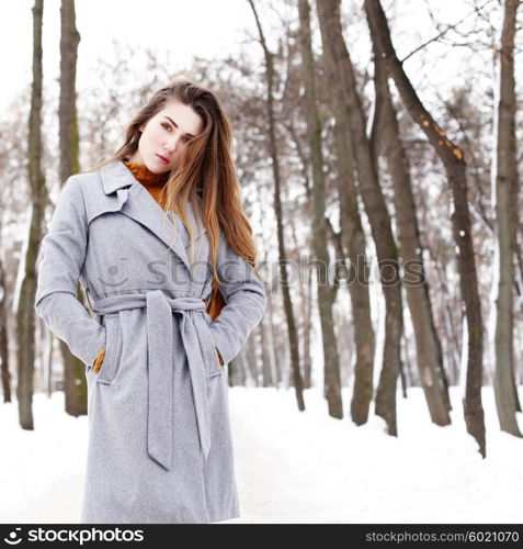 Outdoor winter portrait of young attractive woman in grey long coat posing in the city, street fashion. Pretty sensual girl in winter on the street.