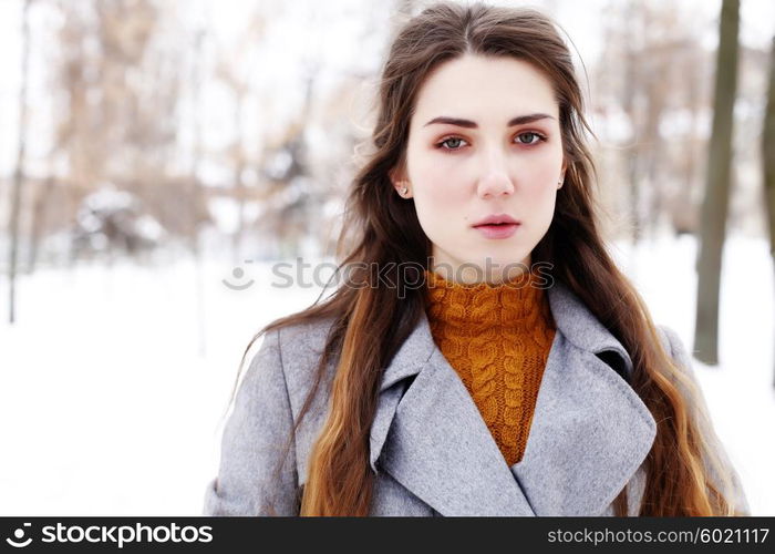 Outdoor winter portrait of young attractive woman in grey long coat posing in the city, street fashion. Pretty sensual girl in winter on the street.