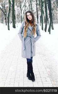 Outdoor winter portrait of young attractive woman in grey long coat posing in the city, street fashion. Pretty sensual girl in winter on the street.