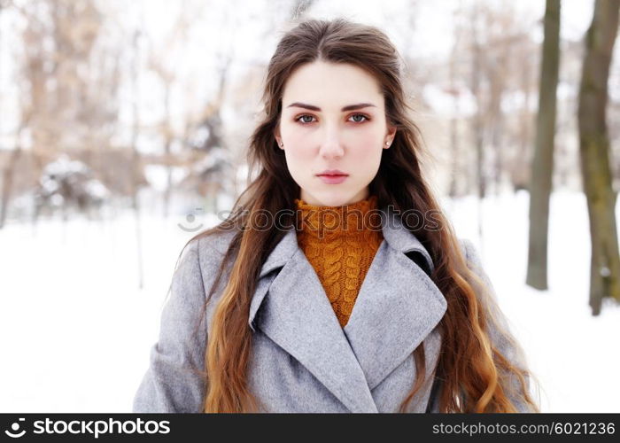 Outdoor winter portrait of young attractive woman in grey long coat posing in the city, street fashion. Pretty sensual girl in winter on the street.