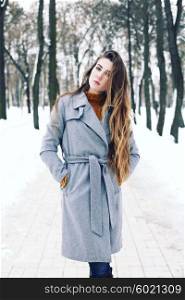 Outdoor winter portrait of young attractive woman in grey long coat posing in the city, street fashion. Pretty sensual girl in winter on the street.