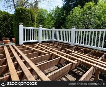 Outdoor wooden cedar deck being remodeled with floor boards being removed