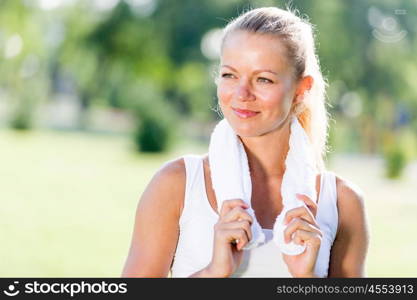 Outdoor workout. Young attractive sport girl in park with towel on neck