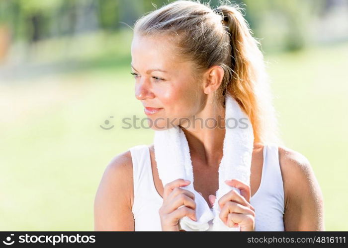 Outdoor workout. Young attractive sport girl in park with towel on neck