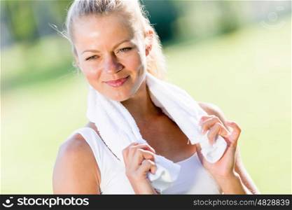 Outdoor workout. Young attractive sport girl in park with towel on neck