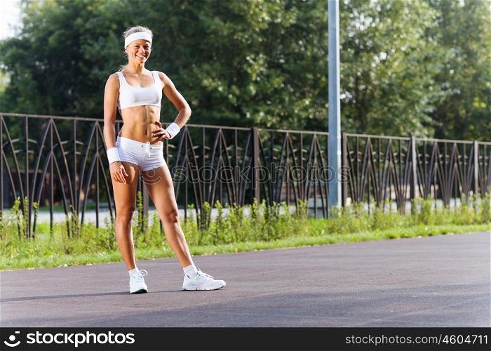 Outdoor workout. Young attractive sport girl in white sport wear in park