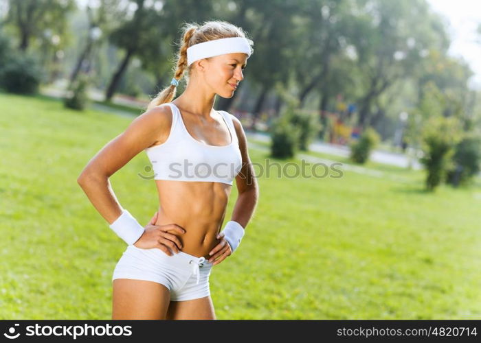 Outdoor workout. Young attractive sport girl in white sport wear in park