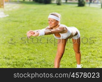 Outdoor workout. Young sport woman in white stretching in park