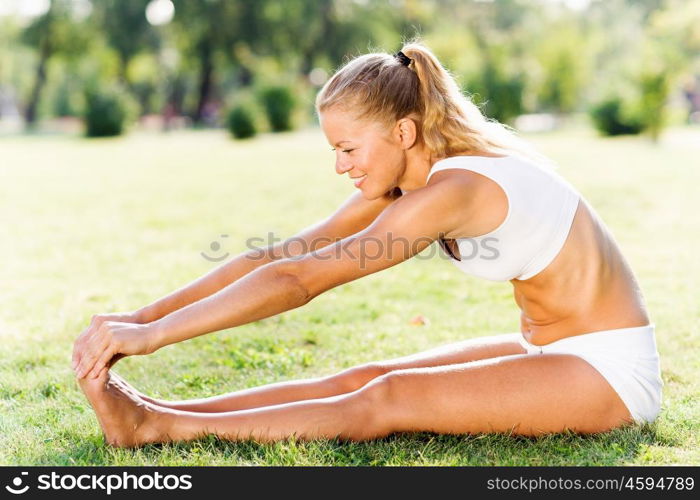 Outdoor workout. Young sport woman in white stretching in park