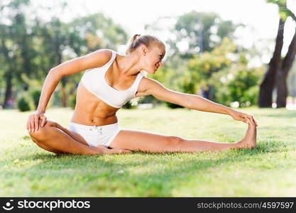 Outdoor workout. Young sport woman in white stretching in park