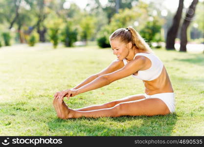 Outdoor workout. Young sport woman in white stretching in park