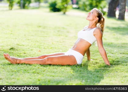 Outdoor workout. Young sport woman in white stretching in park