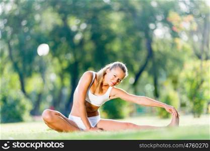 Outdoor workout. Young sport woman in white stretching in park