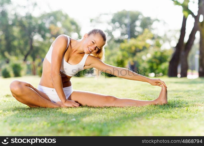 Outdoor workout. Young sport woman in white stretching in park