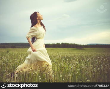 Outdoors art photo of beautiful romantic lady running on dandelions field