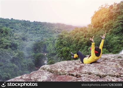 Outdoors excursions on top mountain view cliff / Outdoor adventure and traveler woman relaxing on nature forest tourist on holiday trips adventurous backpacking travel hikes /