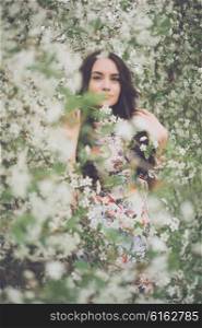 Outdoors fashion photo of beautiful young lady in the garden of cherry blossoms