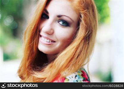 Outdoors portrait of beautiful woman with red hair and smoky eyes makeup. Soft sunny colors. Photo toned style instagram filters