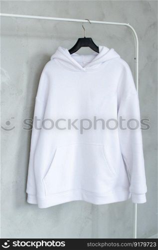 Outerwear, Closet order, White sweatshirt, Green sweater, Pink Sweatshirt, black sweater, Blue sweatshirt, Fold things, men&rsquo;s sweater, Women&rsquo;s sweatshirt, Unisex clothing, Large size, children&rsquo;s clothing. A set of mock-ups of a white hoodie ,pocket, hanging on a hanger, holding in his hands, a sweatshirt with pleats.