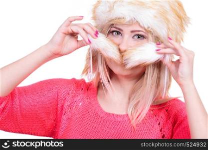 Outfit for cold days ideas, fashion and clothing concept. Attractive smiling blonde woman wearing furry winter hat, hiding behing furr tail. Attractive woman wearing furry winter hat