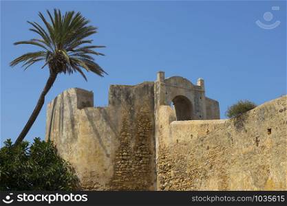 Outside of the old stone fortification wall and gate of Asilah, Morocco with a blue sky