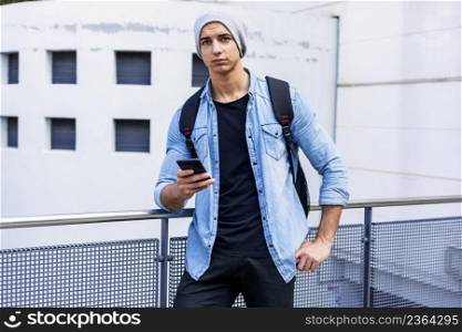 Outside portrait of modern young man with mobile phone in the street.