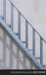 Outside steel staircase structure on gray smartboard wall background in house construction site