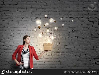 Outside the box thinking. Happy young woman in red jacket opening gift box