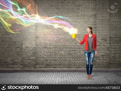 Outside the box thinking. Young woman in red jacket holding yellow bucket in hands