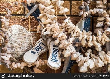 Outside wall decoration at a beach house with a variety of found objects as well as crafted objects, all creating a beach and sea and ocean theme.