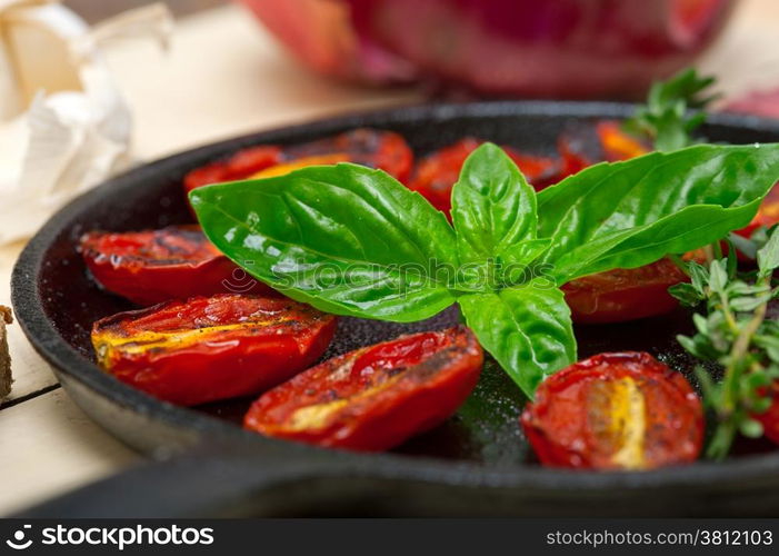 oven baked cherry tomatoes with basil and thyme on a cast iron skillet