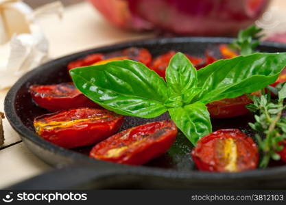 oven baked cherry tomatoes with basil and thyme on a cast iron skillet