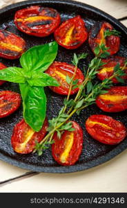 oven baked cherry tomatoes with basil and thyme on a cast iron skillet