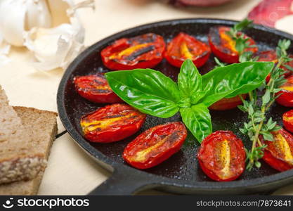 oven baked cherry tomatoes with basil and thyme on a cast iron skillet