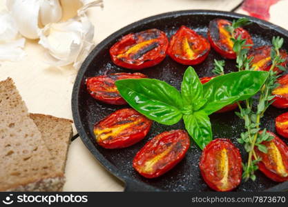 oven baked cherry tomatoes with basil and thyme on a cast iron skillet