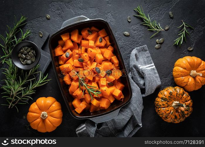 Oven baked pumpkin slices with rosemary and seeds, healthy vegetarian food, top view