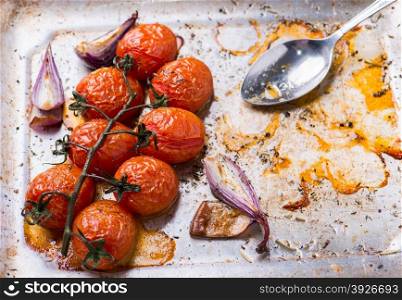 Oven roasted tomatoes and onions on metal baking tray, top view, copy space, selective focus