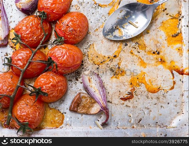 Oven roasted tomatoes and onions on metal baking tray, top view, copy space, selective focus