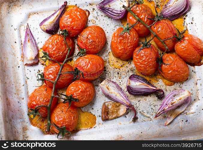 Oven roasted tomatoes and onions on metal baking tray, top view, selective focus