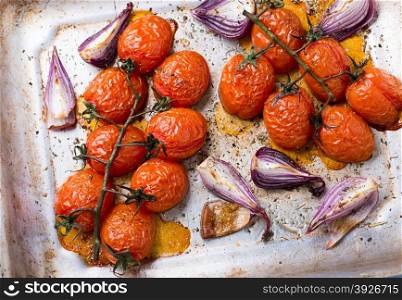 Oven roasted tomatoes and onions on metal baking tray, top view, selective focus