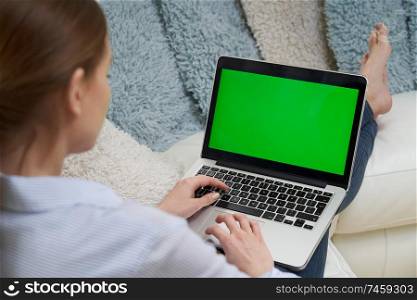 Over The Shoulder View Of Woman Lying On Sofa Using Green Screen Laptop