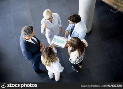 Over view at group of businesspeople standing in the office and analyzing plan
