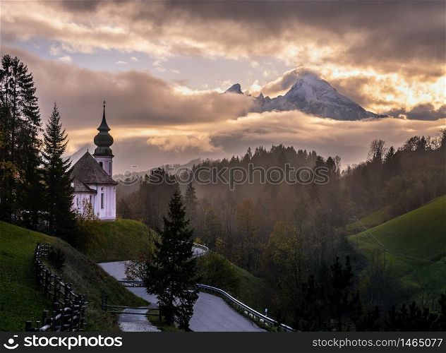 Overcast autumn morning in Bavaria with the small famous Maria Gern pilgrimage church (built in the current form 1708 - 1710) and mount Watzmann top silhouette through fog, Berchtesgaden, Germany
