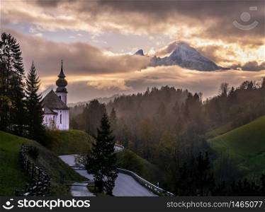 Overcast autumn morning in Bavaria with the small famous Maria Gern pilgrimage church (built in the current form 1708 - 1710) and mount Watzmann top silhouette through fog, Berchtesgaden, Germany