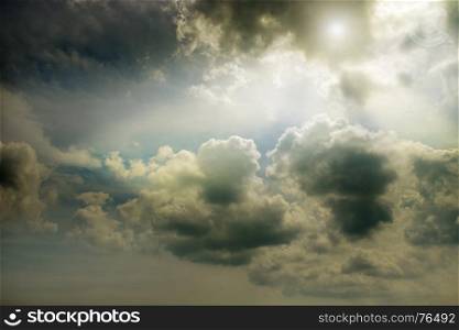 Overcast dark sky and the sun behind cumulus clouds.