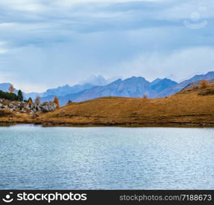 Overcast morning autumn alpine Dolomites mountain scene. Peaceful Valparola Path and Lake view, Belluno, Italy. Picturesque traveling, seasonal, and nature beauty concept scene.