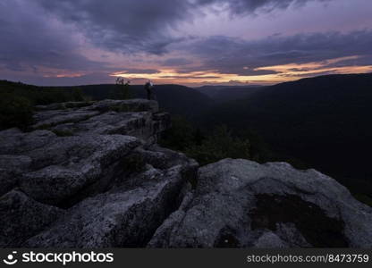 Overcast sunrise views from Table Rock near the Canaan Valley of West Virginia with a backpacker posing on the edge.