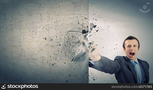 Overcoming challenges. Businessman breaking stone wall with karate punch