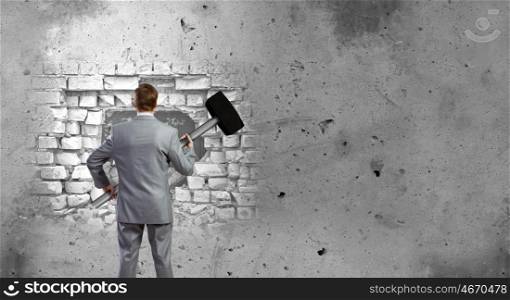 Overcoming challenges. Determined businessman with big hammer in hands