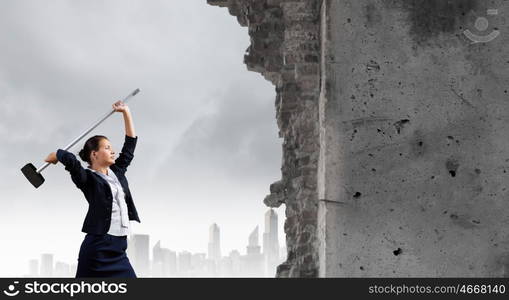 Overcoming challenges. Young attractive businesswoman with hammer in hands